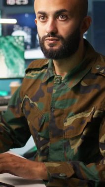 Dikey video özel kuvvetler askeri ajanı kontrol odasında çalışıyor, hava keşif verilerini analiz ediyor. Stratejik hedeflere ve kameralara saldıran İHA 'ları kontrol eden istihbarat uzmanlarına yakın durun.