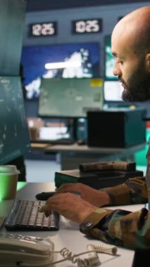 Görev Kontrol Merkezi 'ndeki dikey video askeri ulusal güvenlik operasyonlarını cihazlarla denetliyor. Kapatın. Ortadoğu ordu uzmanı gözlem odasındaki verileri inceliyor.