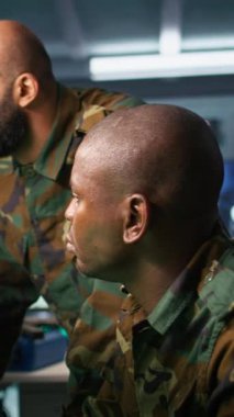 Meslektaşının yanındaki devlet tesisinde çalışan dikey video ordu birimi dijital ekipmanlarla izleme teknolojisi kullanıyor. Operasyon üssünde çalışan Afrikalı Amerikalı adam, kamera.