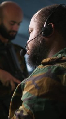 Ön saflarda savaşan komutanlara bilgi sağlamak için kulaklık mikrofonu kullanan dikey video askeri hareket memuru. Operasyon üssündeki birliklere istihbarat sağlayan ordu uzmanı, kamera A