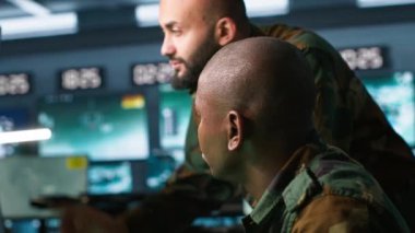 Meslektaşının yanındaki hükümet tesisinde çalışan ordu birimi dijital ekipmanlarla izleme teknolojisi kullanıyor. Operasyon üssünde işini yapan Afrikalı Amerikalı adam, kamera A.