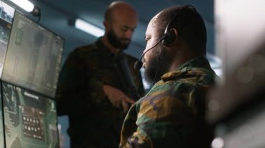 Askeri sevkiyat memuru, ön saflarda savaşan komutanlara bilgi vermek için kulaklık mikrofonu kullanıyor. Operasyon üssündeki birliklere istihbarat sağlayan ordu uzmanı, kamera A