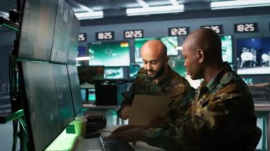 Ordu birimi iş arkadaşının yanındaki devlet tesisinde çalışıyor, beyin fırtınası yapıyor, gözetleme teknisyenliği yapıyor. Operasyon karargahında görev yapan bir grup asker, kamera B