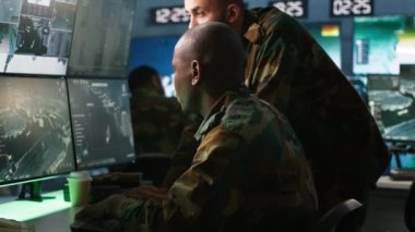 Ordu telekomünikasyon operatörleri radyo ve uydu donanımı kullanarak sistemlere veri giriyorlar. İletişim ağlarını yöneten askeri sevkiyatçılar, klavyede daktilo, kamera A