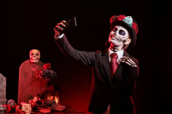 stock image Lady posing for social media photos during Dia de los Muertos, preserving cultural traditions. Woman taking selfie pictures with phone, wearing la Catrina costume to celebrate Mexican culture