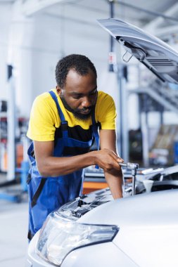 Mühendis, otomotiv performansını ve güvenliğini sağlamak için gelişmiş mekanik araçlar kullanarak araç ateşleme sistemini ustalıkla inceliyor. Tecrübeli garaj çalışanı yıllık araç kontrolü yapar.
