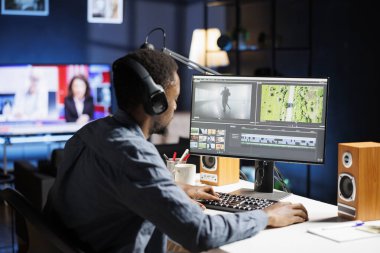 Afrikalı Amerikalı editör evde renk düzeltme yazılımıyla video montajı üzerinde çalışıyor ve video arayüzü üzerinde görsel efektler yaratıyor. Ortam tasarımcısı film segmentleri düzenliyor.