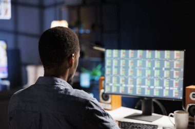 Finansal danışman, internet üzerinden küresel döviz istatistikleri bilgisayarına bakarak, evindeki iş yerindeki kripto döviz piyasasını inceliyor. Sermaye fonlarını güvence altına almak için hisse senedi analizi okuyan genç..