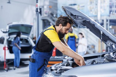Araba servisi teknisyeni gelişmiş mekanik aletler kullanarak motoru ustalıkla inceliyor, düzgün bir otomotiv performansı ve güvenliği sağlıyor. Uzman bir garaj uzmanı rutin araç kontrolü yapıyor.
