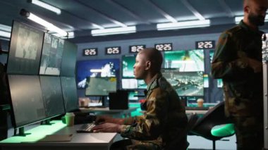 Askeri üste dijital radar ekipmanları ve çalışan füze sistemleri ile gözetleme yapan bir istihbarat ajanı. Afrika kökenli Amerikalı bir adam, ordu merkezinin güvenlik kameralarına izinsiz hareketlilik var mı diye bakıyor.