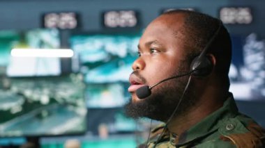 Askeri sevkiyat subayı, ordu istihbarat analistlerinden cephedeki birliklere bilgi aktarıyor, yakın çekim. Üniformalı telsiz iletişim operatörü mikrofon ve kamera A ile konuşuyor.