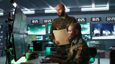 Askeri karargahtaki asker iş arkadaşıyla beyin fırtınası yapıyor, düşman birlikleri hakkında bilgi topluyor. Takım çalışanları, düşman savunmasızlıklarını değerlendirmek için izleme yazılımı kullanıyor.