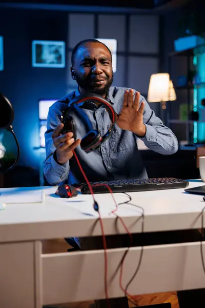 stock image Content creator in dimly lit living room uses camera to film wired headphones review for online streaming platforms. Online star unboxing music listening device, giving it low rating feedback