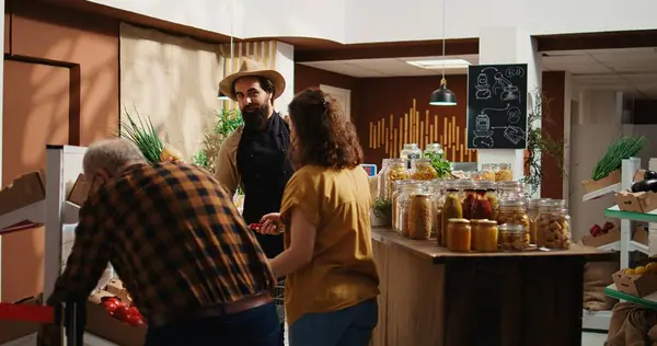 stock image Owner greets first clients during green living zero waste supermarket grand opening, removing red ribbon. Entrepreneur welcomes shoppers inside low carbon footprint local grocery store, tracking shot