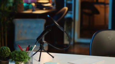 Profesyonel mikrofonlu sehpanın yakın çekimi ve loş ışıklı mini ev yapımı bitkiler. Oturma odasında RGB ışıklarıyla aydınlatılmış canlı kayıt ekipmanları.