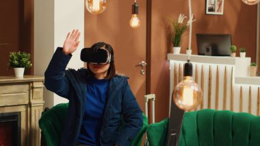 Asyalı kız kayak pistinde kayak yapmadan önce sanal gerçeklik teknolojisiyle eğlenmek için lobide VR gözlükleri kullanıyor. Kış sporları için modern kulaklık kullanan bir kadın..