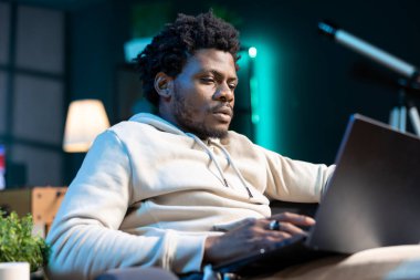 Evden e-posta göndermek için dizüstü bilgisayar kullanan serbest çalışan bir adam. Klavyeye yazı yazan Afrikalı Amerikalı bir adam, nihai projeyi müşteriye ulaştırmak için belgeler hazırlıyor.