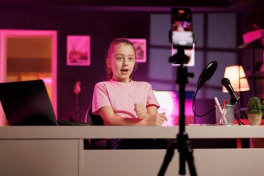 Üç ayaklı telefondan aile videolarını çeken bir kız. Okulda çocukların izlediği bir günden bahsediyor. Çocuk akıllı telefonla çevrimiçi kanal için içerik kaydediyor, hayranlarla tartışıyor