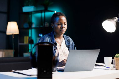 Dijital bilgisayarını kullanarak tezini internette araştırmakla meşgul bir bayan öğrenci. Kendini işine adamış Afro-Amerikan bağımsız blog yazarı, işi için modern teknolojiden yararlanıyor..