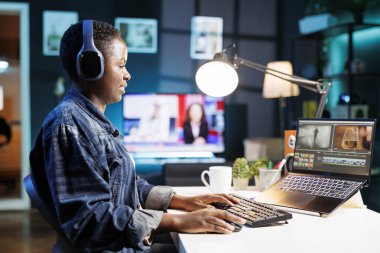 Black woman immersed in world of technology, wearing wireless headphones as she edits photos and videos. African american female filmmaker working with footage and sound, editing new project. clipart