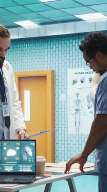 Dikey Video Radyologları ve uzmanları tedavi planları için x ışını test sonuçlarını inceliyorlar. Bir grup lisanslı sağlık uzmanı sigorta hizmetleri için özel bir klinikte çalışıyorlar.
