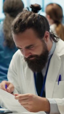 Doktorlardan oluşan dikey video ekibi, kabinede tehlikeli bir hastalığa teşhis koyan uzman doktoru alkışlıyor. Mutlu yetenekli doktorlar sağlık hizmetlerinin başarısını kutluyor.