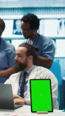 Kroma anahtar ekranının yanında hastane kayıtlarına bakan doktorların dikey video grubu teşhisi incelemek için x ışını test sonuçlarını kullanıyor. Tedavi için özel klinikte çeşitli uzmanlar toplandı