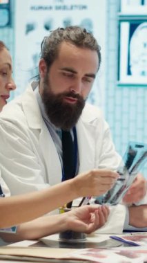 Tedavi protokolleri ve iyileştirmeleri tartışan bir toplantıda dikey video sağlık uzmanları. Tıbbi hizmetlerin kalitesini artırmak için özel bir klinikte teşhis sonuçlarını değerlendiren doktorlar ve hemşireler