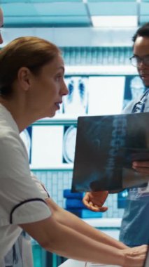 Dikey Video Doktorları ve radyologlar etkili bir tedavi planı oluşturmak için röntgen taramalarını analiz ediyorlar. Sağlık hizmetleri için radyografiye dayalı teşhisleri sağlamak için özel bir klinikte ekip çalışması yapan sağlık görevlileri