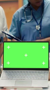 Doktorlardan oluşan dikey video ekibi, tıbbi kabinedeki bilgisayarın yanında analitik danışmanlık yapıyor. Teşhisi bulmak için röntgen taraması sonuçlarını inceliyorlar. Lisanslı sağlık görevlileri hastane kayıtlarını inceliyor.