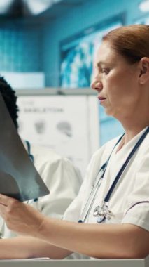Personelle toplantı sırasında test sonuçlarını ve radyografiyi analiz eden özel bir klinikte dikey video uzmanı. Lisanslı sağlık görevlileri hastalık önleme için tedavi seçeneklerini araştırıyor. Kamera A.