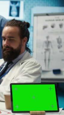 Dikey video çeşitliliğindeki sağlık ekipleri fotokopi alanının yanındaki röntgenleri analiz eder ve tıbbi bir ofiste tedavi planlarını tartışırlar. Sağlık uzmanları sigorta teşhisi koymaya çalışıyorlar. Kamera.