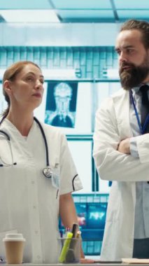 Tıbbi uzmanlardan oluşan dikey video ekibi, kabinede holografik bir görüntü kullanarak teşhis verilerini ve hastane kayıtlarını inceliyor. Uzmanlar klinikteki hologramla ilgili tedavi planlarını inceliyor. Kamera A.