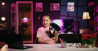 Genç içerik yaratıcısı, internetteki sosyal medya içeriğini izleyen çocuklar arasında popüler olan akıllı telefonu eleştirirken kendini çekiyor. Telefon özelliklerini sunan mutlu küçük etkili video kaydı