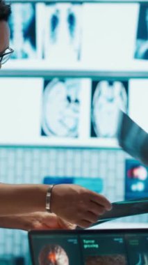 Dikey Video Uzmanı doktor ekiple test sonuçları ve teşhisleri tartışıyor, özel bir klinikteki toplantıya katılıyor. Hastalıkların önlenmesi için tedavi planlarını araştıran pratisyen hekimler