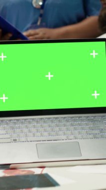Krom anahtar ekranının yanında hastane kayıtlarına bakan doktorların dikey video grubu teşhisi incelemek için x ışını test sonuçlarını kullanıyor. Çeşitli uzmanlar bir tedavi planı sunmak için klinikte toplanıyorlar.