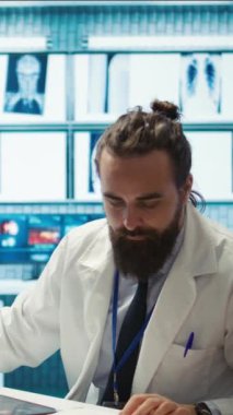 Dikey Video Yorgun Endişeli doktor bir hastanın teşhisini bulmak için saatler sonra çalışıyor, çok stresli hissediyor ve tıbbi kabinede röntgen sonuçlarını incelemeye çalışıyor. Hüsrana uğramış çok çalışan doktor.