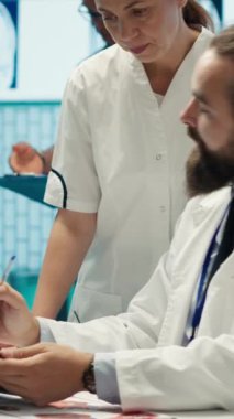 Dikey Video Uzmanları ekibi tedavi hizmetini geliştirmek için test sonuçlarını inceleyerek potansiyel tanı ve sigortayı tartışıyor. Tıbbi yardım sağlamak için birlikte çalışan profesyonel sağlık görevlileri