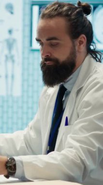 Dikey Video Yorgun Endişeli doktor bir hastanın teşhisini bulmak için saatler sonra çalışıyor, çok stresli hissediyor ve tıbbi kabinede röntgen sonuçlarını incelemeye çalışıyor. Hüsrana uğramış çok çalışan doktor.