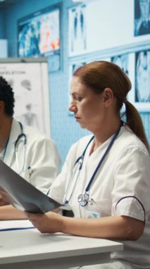 Personelle toplantı sırasında test sonuçlarını ve radyografiyi analiz eden özel bir klinikte dikey video uzmanı. Lisanslı sağlık görevlileri hastalık önleme için tedavi seçeneklerini araştırıyor. Kamera B.