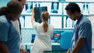Radyologlar ve uzmanlar tedavi planları için x ışını test sonuçlarını inceliyorlar. Bir grup lisanslı sağlık uzmanı özel bir klinikte sigorta hizmetleri sağlamak için çalışıyorlar. Kamera A.