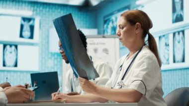 Personelle toplantı sırasında test sonuçları ve radyografiyi analiz eden özel bir klinikte tıbbi uzman. Lisanslı sağlık görevlileri hastalık önleme için tedavi seçeneklerini araştırıyor. Kamera A.