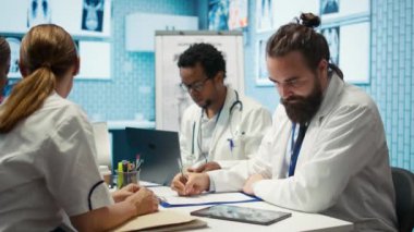 Hekim, kabinesinde hastalık önleme için ilaç öneren bir tedavi planı yazıyor. Klinikteki tıbbi danışmanlık analizleri ve hastane kayıtları. Kamera B.