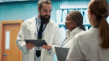 Doktor ve hemşireler hastane ortamında en iyi tedaviyi sunmayı hedefleyen sağlık raporlarını ve test sonuçlarını gözden geçiriyorlar. Muhtelif sağlık görevlileri kontrol için sağlık kayıtlarına bakıyorlar. Kamera A.