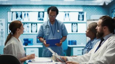 Lisanslı hemşire, araştırma seansı için ekiple görüşüyor. Kişisel tıbbi hizmetler. Bir klinikte tedavi planları üzerinde çalışan çeşitli sağlık uzmanları. Kamera B.