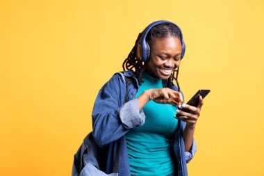 Gülümseyen Afrikalı Amerikalı kadın web sitesine ödeme metodu ekliyor, promosyonların keyfini çıkarıyor, stüdyo geçmişi var. İnternet alışverişi yapan, akıllı telefondan kredi kartı bilgilerini yazan mutlu bir genç.