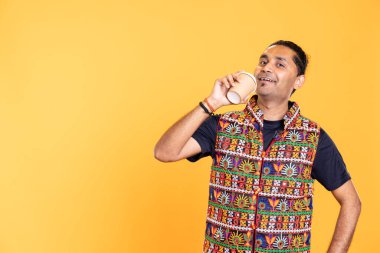 Mutlu Hintli bir adamın portresi sabahın erken saatlerinde uyanmak ve enerjik olmak için kullan-at kağıt bardaktan taze kahve yudumluyor. Neşeli insan sıcak bir içecek içiyor, keyifli bir ruh hali, stüdyo geçmişi var.