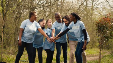 Joyful optimistic group of activists unites to clear out the woods, enjoying their voluntary efforts by locking hands. Satisfied people adopting devotion towards the environment. Camera A. clipart