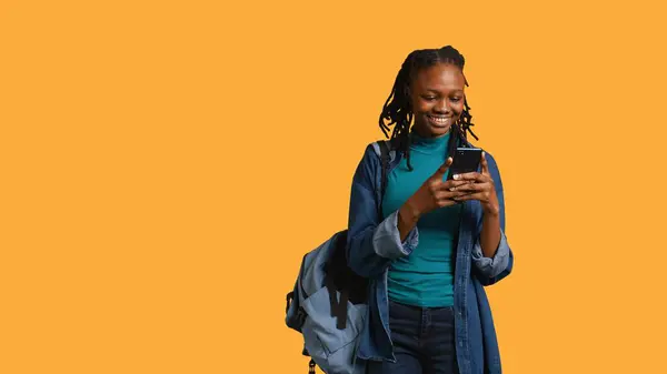 stock image Portrait of overjoyed teenager reading messages on phone, delighted after receiving good news. Woman excited by SMS on smartphone, celebrating, studio background, camera B