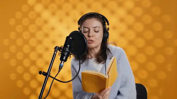 stock image Voice actor reading book, recording for audiobook production using microphone and headset, studio background. Person using mic and headphones to produce digital recording of novel, camera B